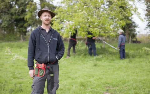 Laurence standing in an orchard