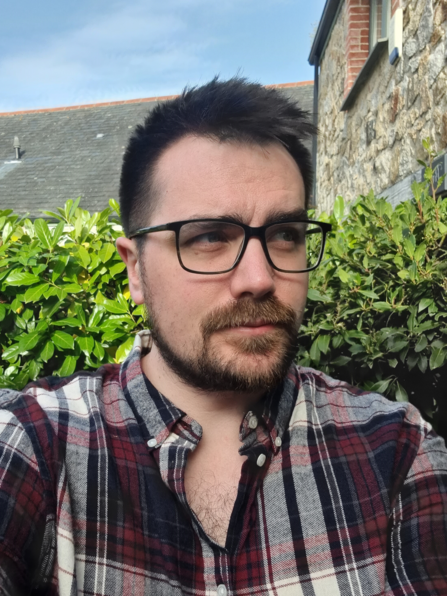 Rob Gordon stood outside in a garden, with a hedge visible behind him